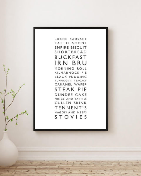 Minimalist framed wall print, displaying a vertical list of iconic Scottish foods and drinks in clean black typography on a white background. The design features items such as lorne sausage, tattie scone, Irn Bru, Buckfast, steak pie, Cullen skink, Tennent’s, and stovies. Styled in a neutral interior.
